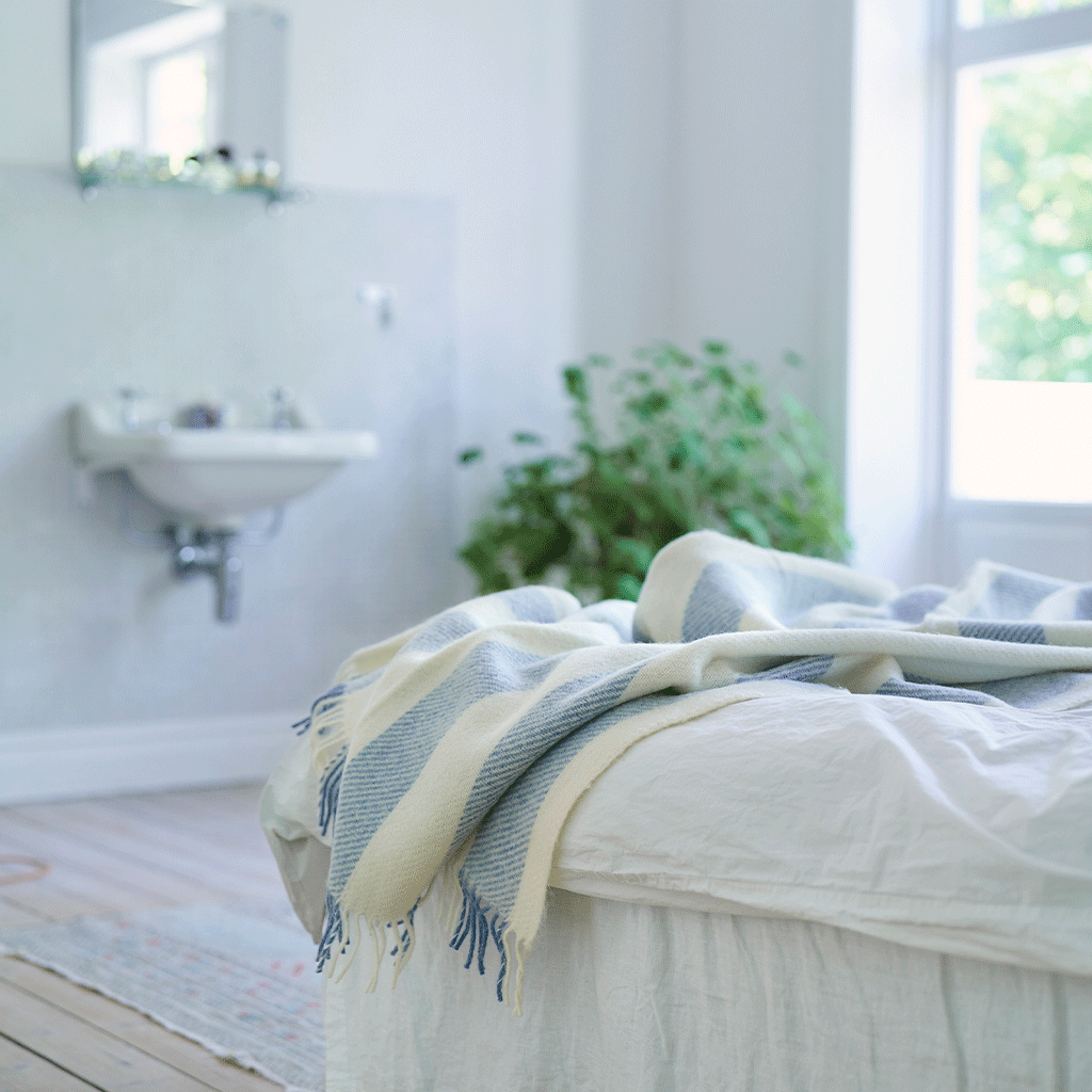 Klippan's Gotland vertical Stripe throw in blue and white on a white bed