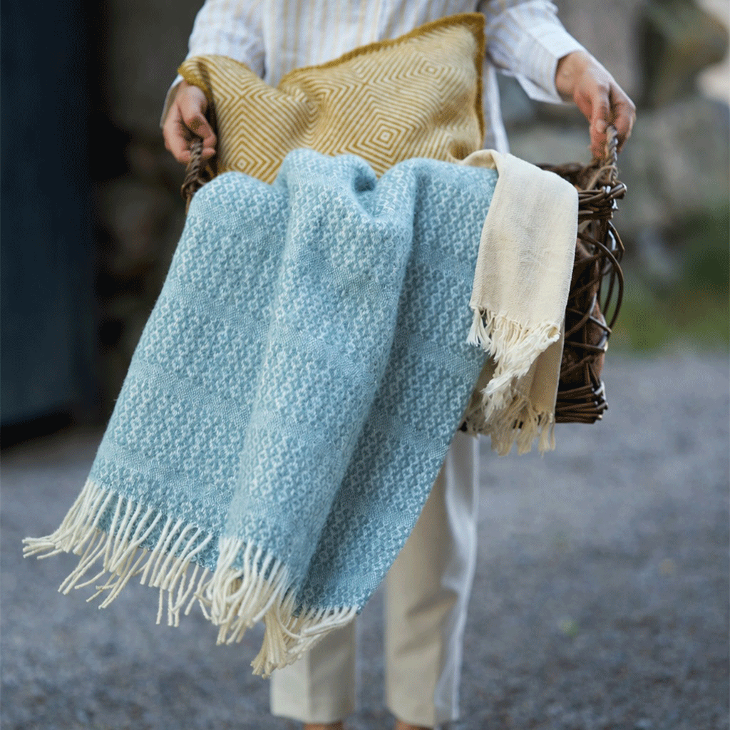 Klippan beautiful sky blue throw called Porto being carried in a basket