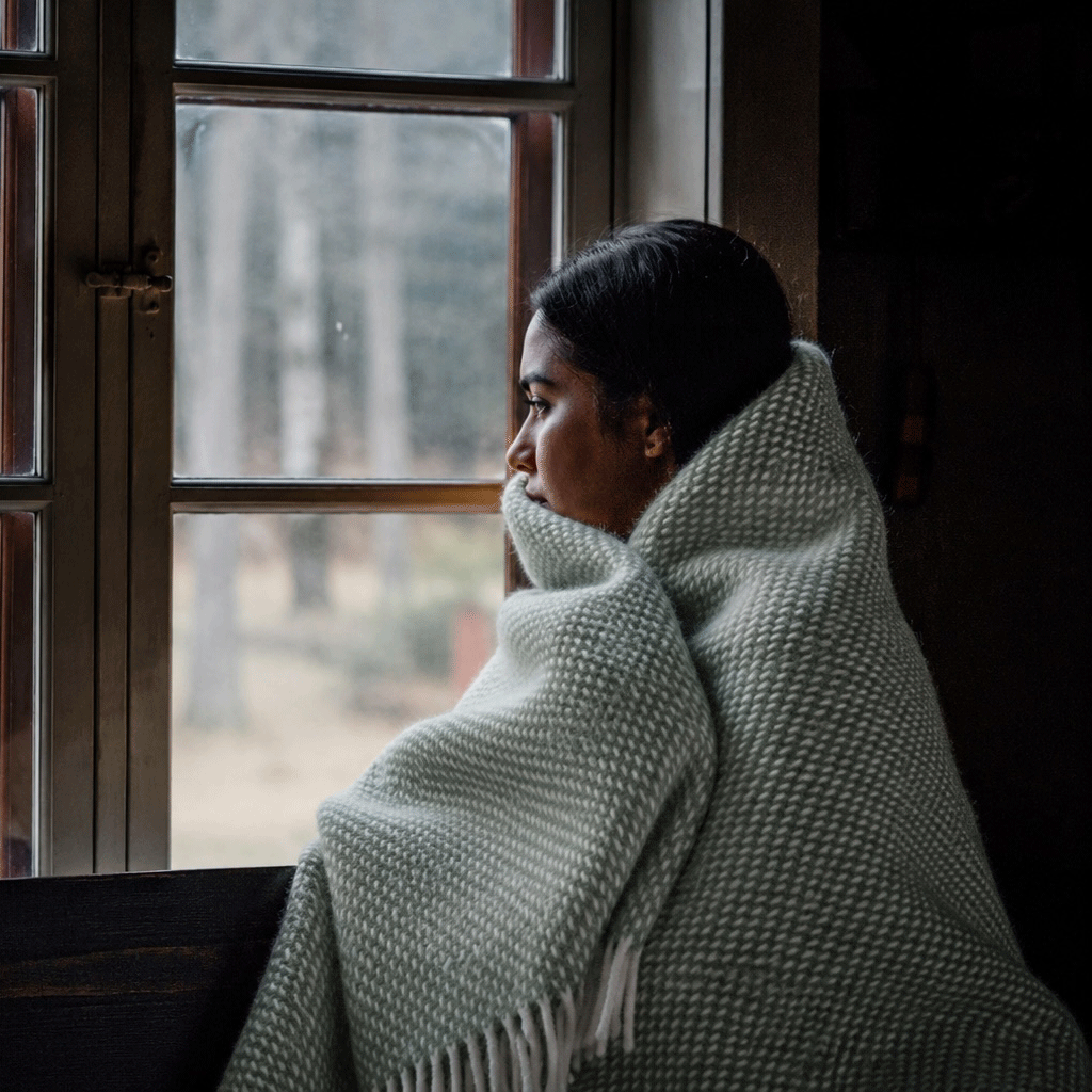 Girl by a window wrapped in Preppy green throw from Klippan Homestore