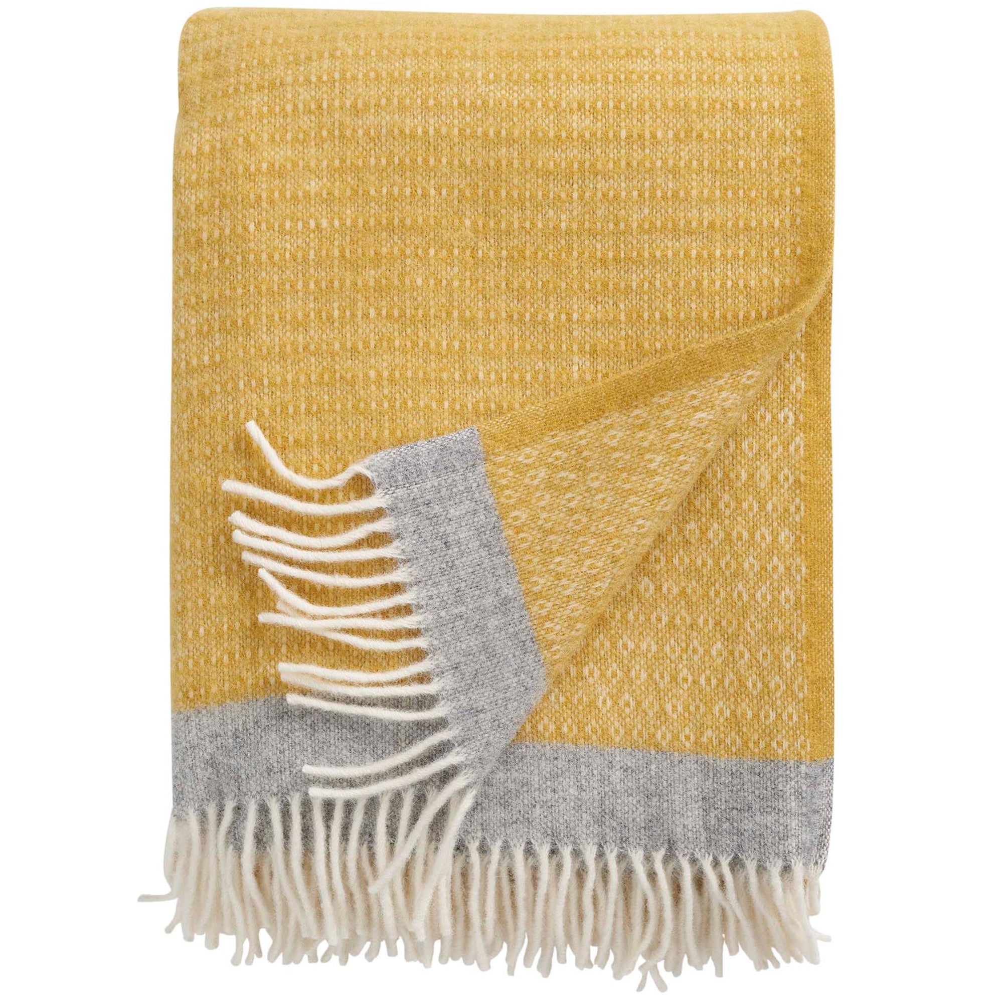 A yellow eco lambswool throw with gray trim and fringes, displayed on a flat surface.