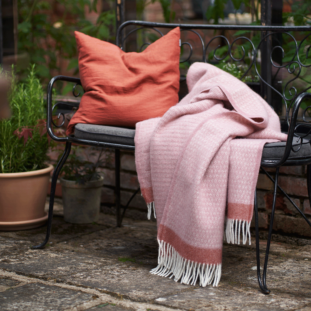 Klippan's Harald throw in dusty rose on a garden bench