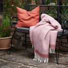 Klippan's Harald throw in dusty rose on a garden bench