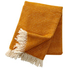 A mustard yellow eco lambswool throw with a textured weave and fringes on the ends.