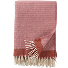 A dusty rose colored eco lambswool throw with fringes, displayed on a white background.