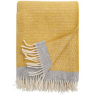 A yellow eco lambswool throw with gray trim and fringes, displayed on a flat surface.